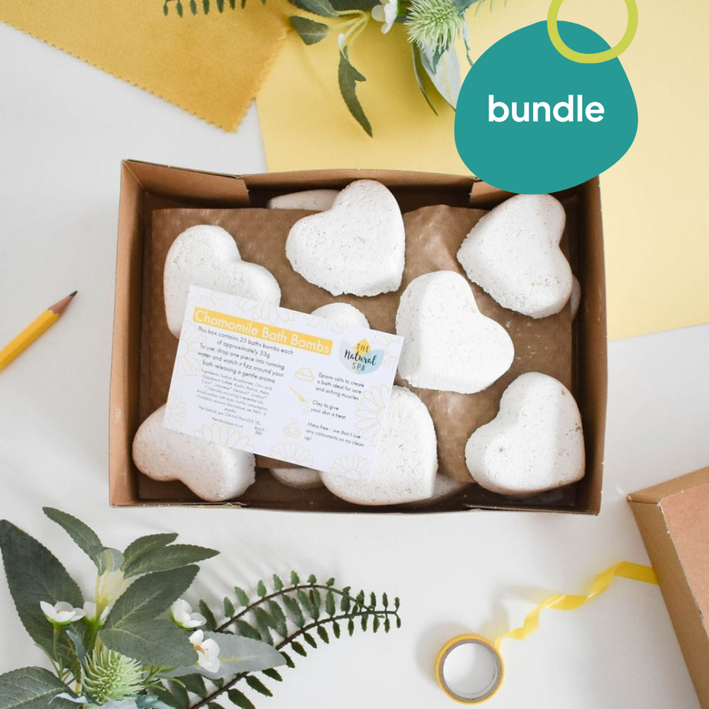 A bundle of heart-shaped bath bombs displayed in an open gift box with a 'bundle' label, surrounded by decorative elements and a card.