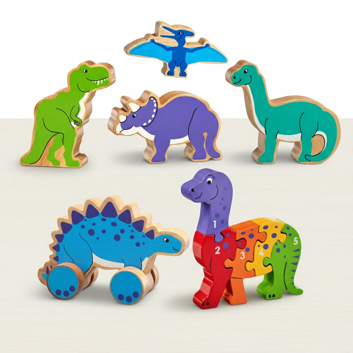 Set of colourful dinosaur play figures, with a stegosaurus push along toy and a diplodocus wooden puzzles on a light background