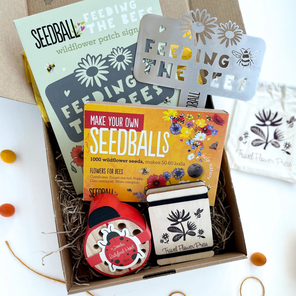 Open Nature Garden Gift Box showing seedball kit, travel flower press, 'Feeding the Bees' sign, ladybird bug hotel, and arranged in a kraft gift box 