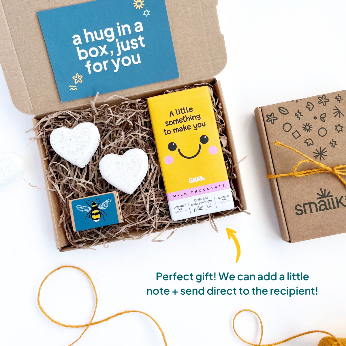 Something to Make You Smile Gift Box by Smallkind including two heart shaped bath bombs., a box of seedballs and a milk chocolate bar with a 'something to make you smile message'. text on the image read 'perfect gift! We can add a little note and send direct to the recipient!