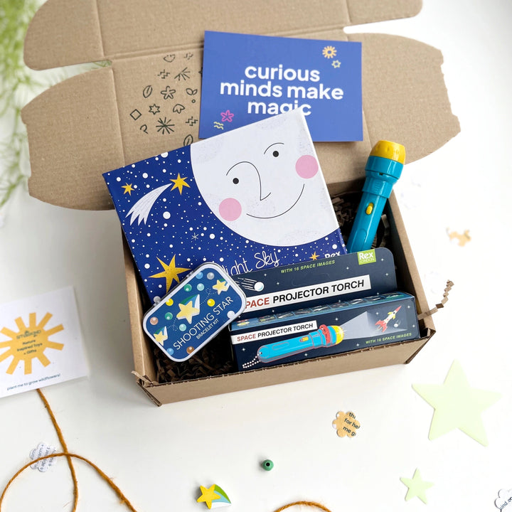 Educational toy set with space-themed toys and craft kits in a cardboard box on a white background.