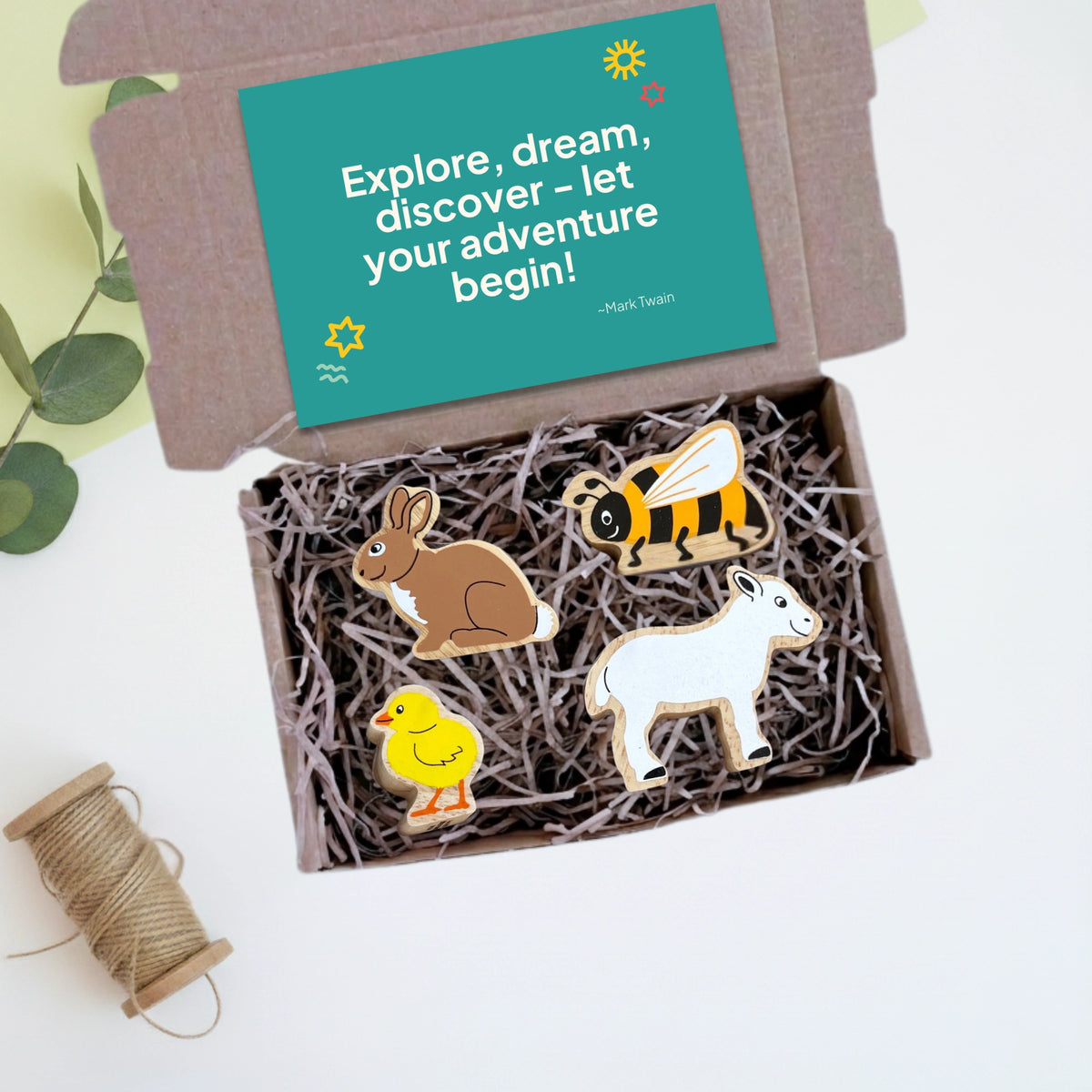Box with wooden animals - rabbit, bee, chick and lamb - and a motivational card on a light background