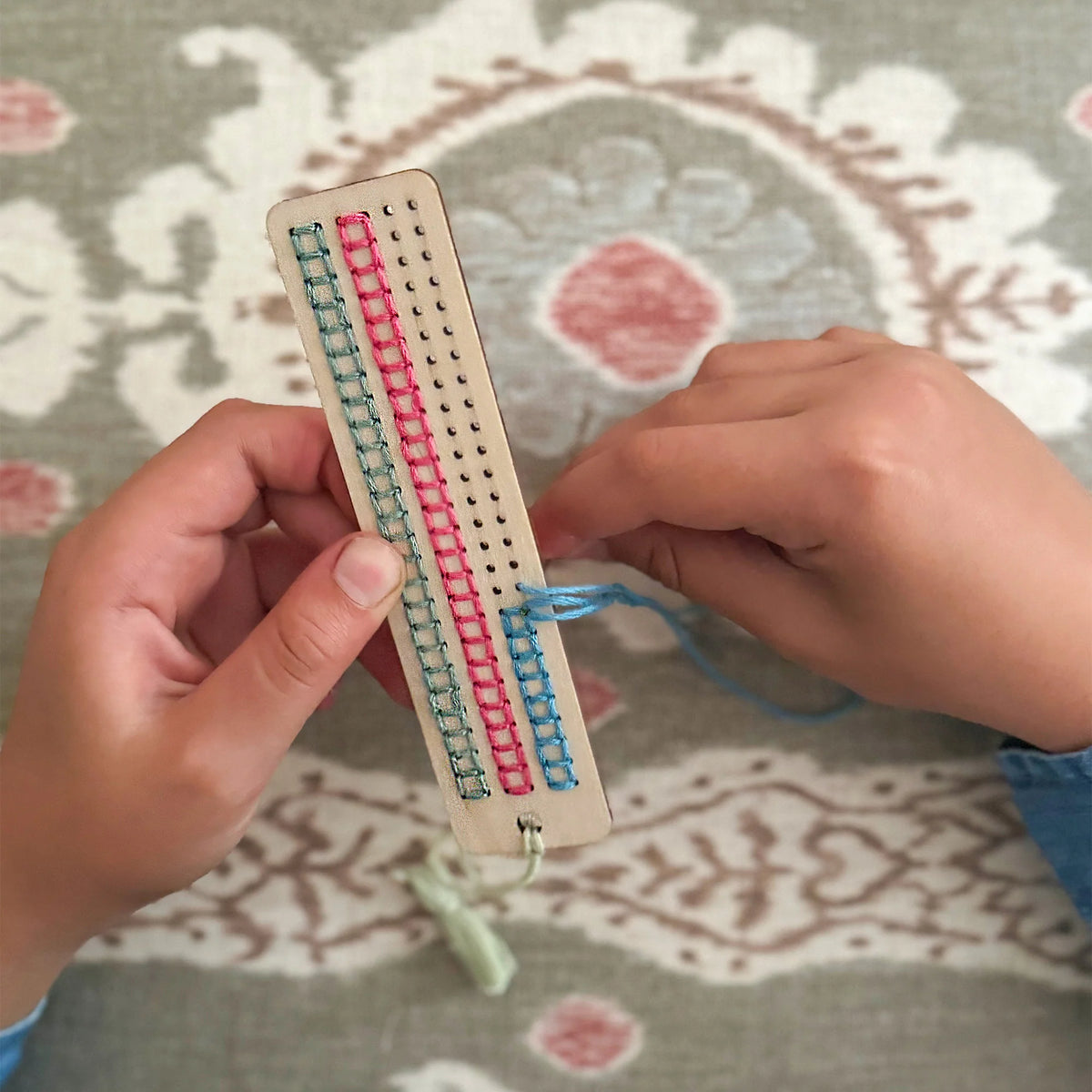 childs hands stitching a Cotton Twist make your own stitched tassel bookmark craft kit for children and adults. 