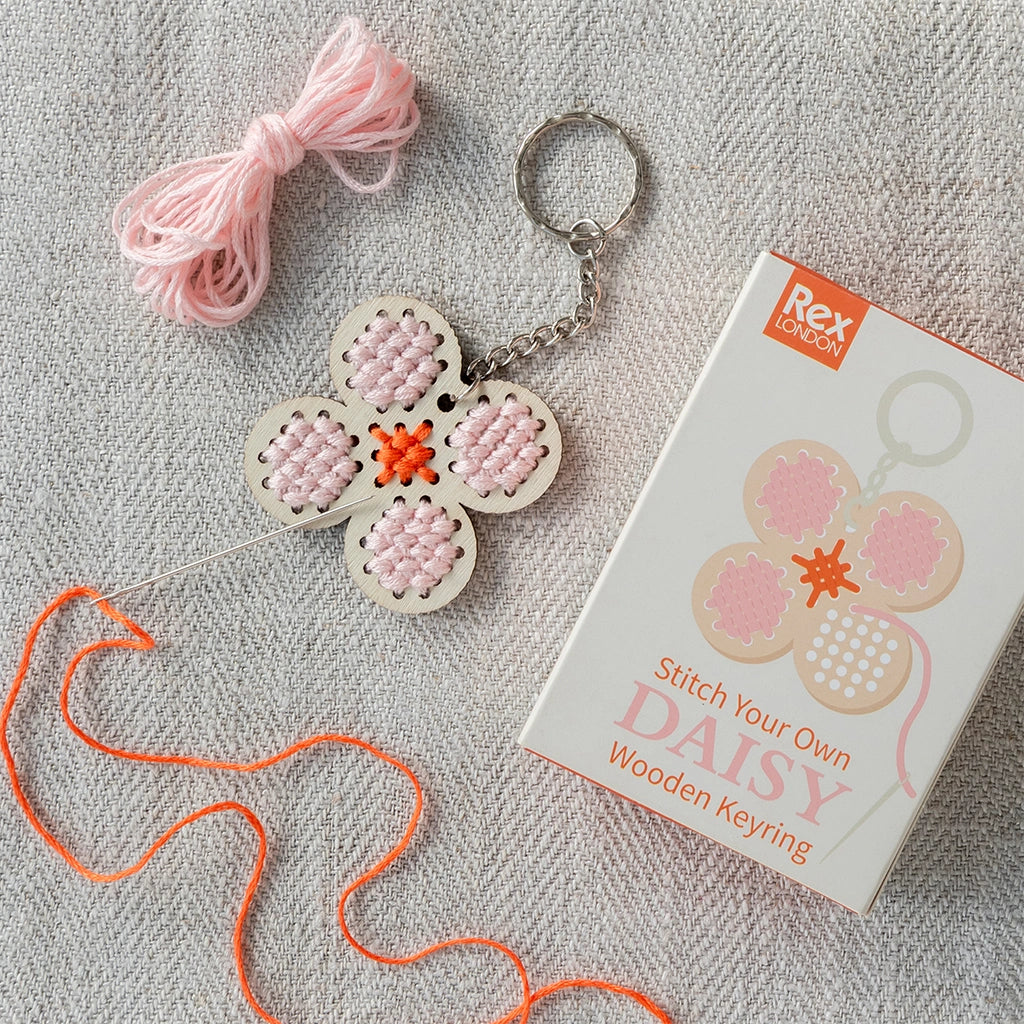  Stitch Your Own Wooden Daisy Keyring Craft Kit on a beige tablecloth with a gift box. 