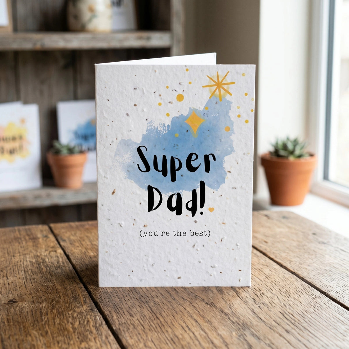 Greeting card with 'Super Dad! (you're the best)' text on a wooden surface.