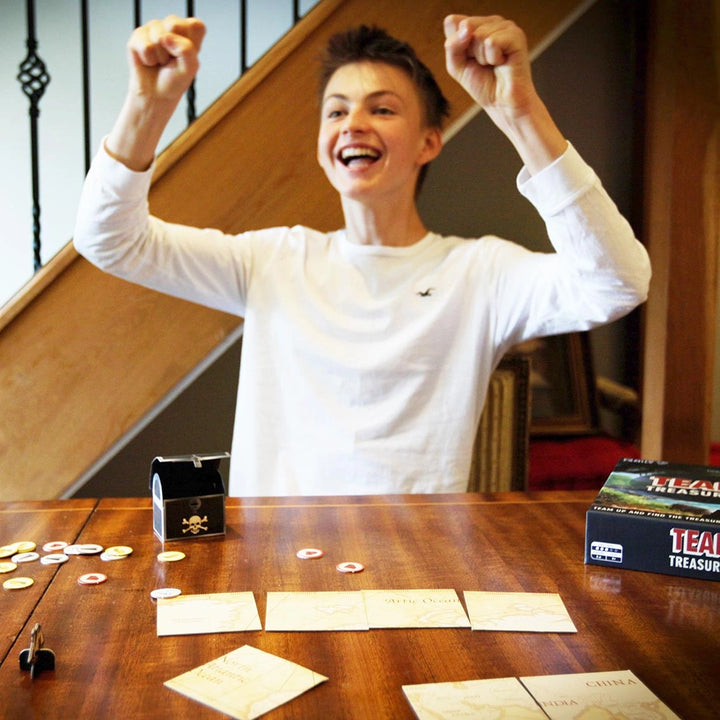 Person celebrating at a table with board game components