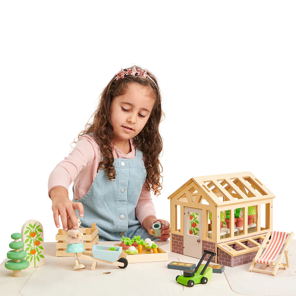 girl playing with Tender Leaf Green House and Garden Set including wooden greenhouse and accessories. For age 3+ 