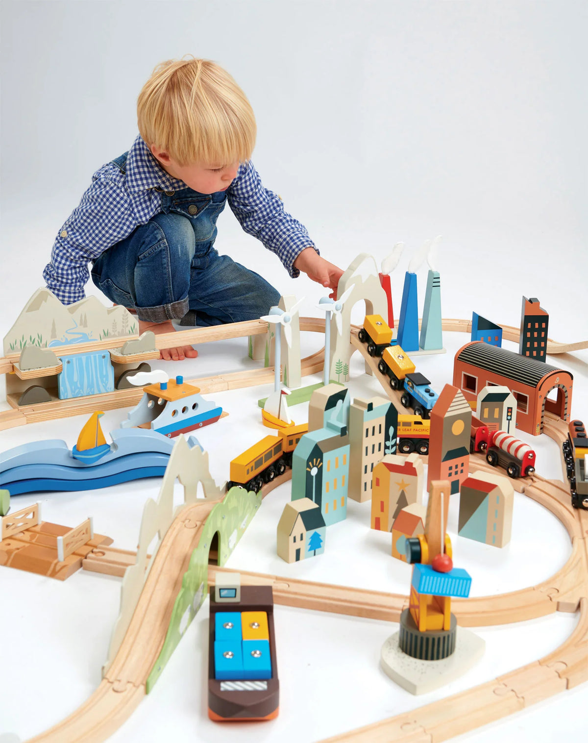 boy playing with Tender Leaf Toys Mountain View Train Set with colourful buildings, tunnels and bridges. For children age 3+ 