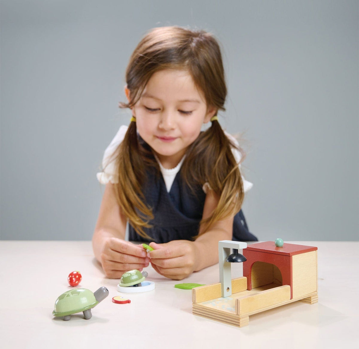 Girl playing with a Tender Leaf wooden Tortoise Pet Set complete with mum and baby tortoise with a house and accessories.