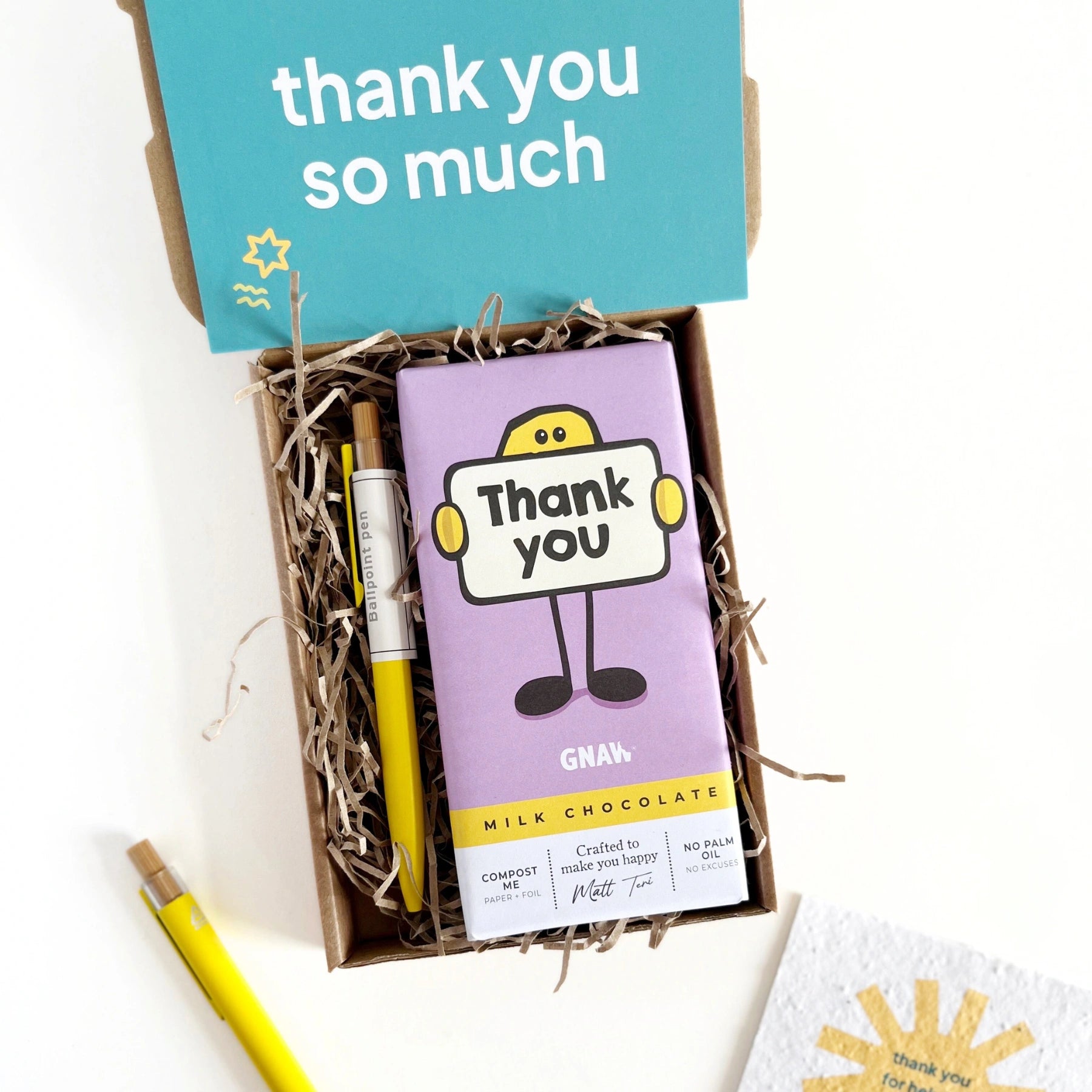 Gift box with chocolate bar, pencils, and a card that says 'thank you so much'.