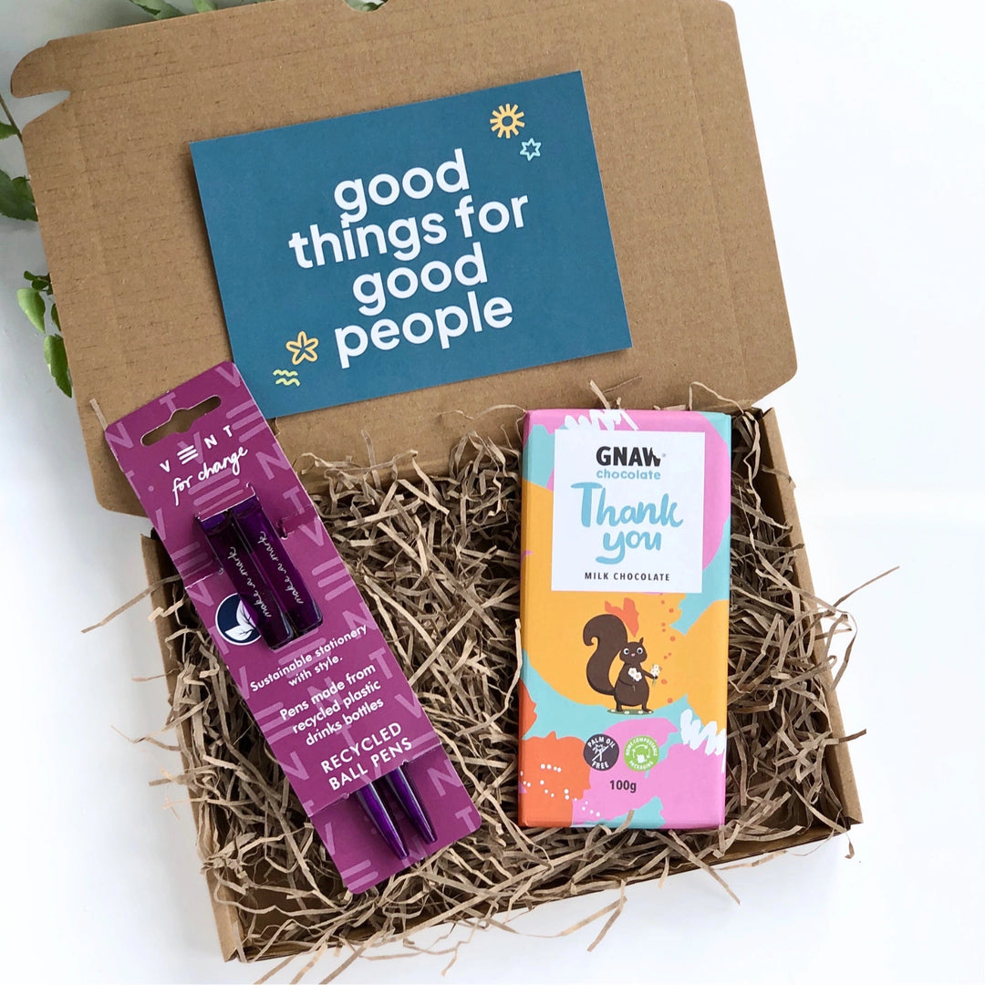 set of two purple recycled pens and a chcolate bar in a colourful wrapper with a thank you message. The products are inside a kraft gift box filled with shredded recycled paper and comes with a green card with 'goog things for good people' in white bold text. 