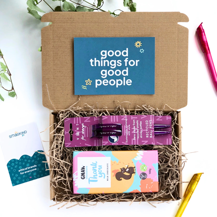 a bar of milk chocolate with colourful 'thank you' wrapping and a set of two purple recycled pens. The products are inside a kraft gift box filled with shredded paper and a card which reads 'good things for good people'. This stationery gift box is perfect for colleagues, staff and teacher gifts.