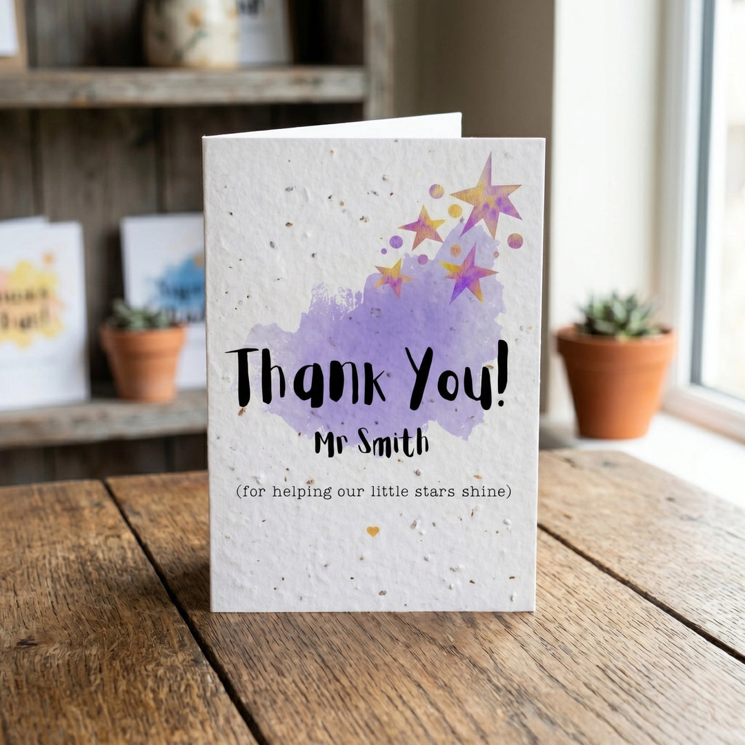 Greeting card with 'Thank You! Mr Smith' text on a wooden surface with plants in the background