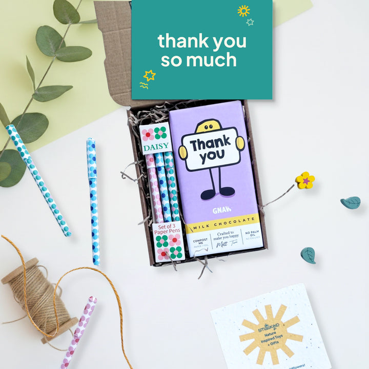 Gift set with chocolate bar, paper pens and a card on a light background