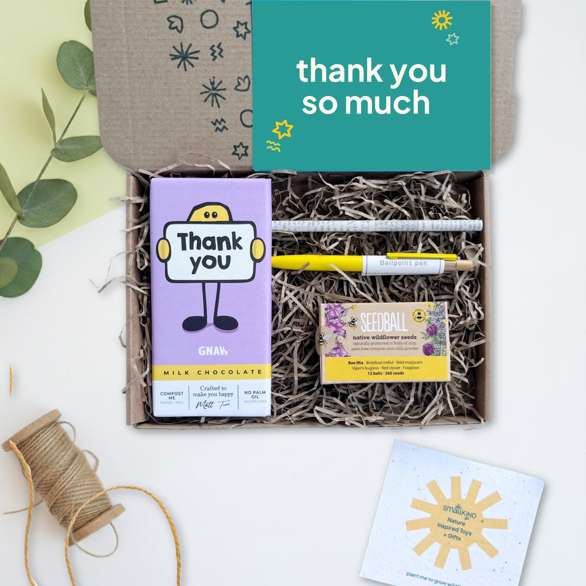 Gift box with chocolate bar, pen, and card on a light background