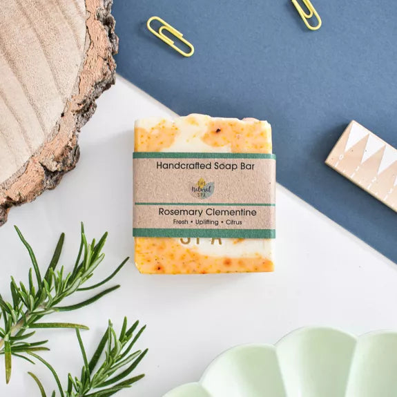 handmade cold process soap bar - rosemary clementine which is orange and cream coloured. packaged in a paper wrapper