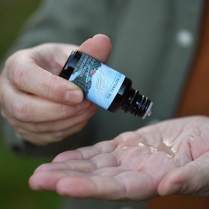 mans hands with open bottle of The Outdoorsman Beard Oil