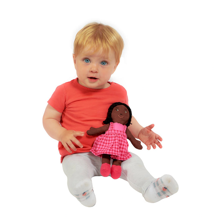 Child holding a doll with black braided hair and black skin, on a white background