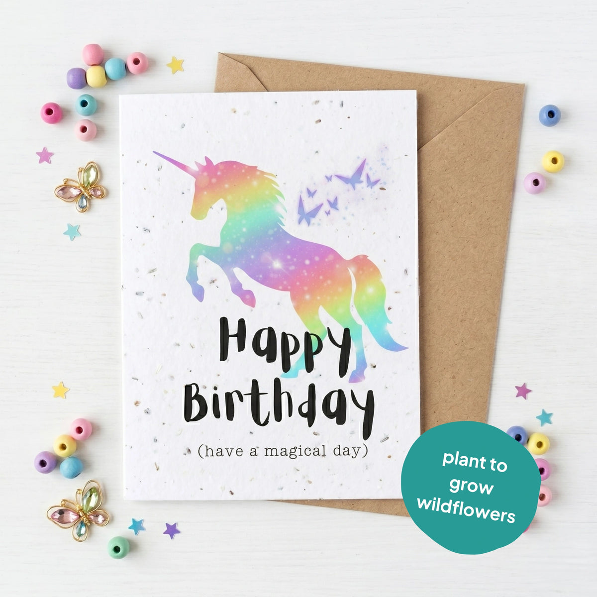 Birthday card with a rainbow unicorn and 'Happy Birthday' text, surrounded by decorative items on a white background.