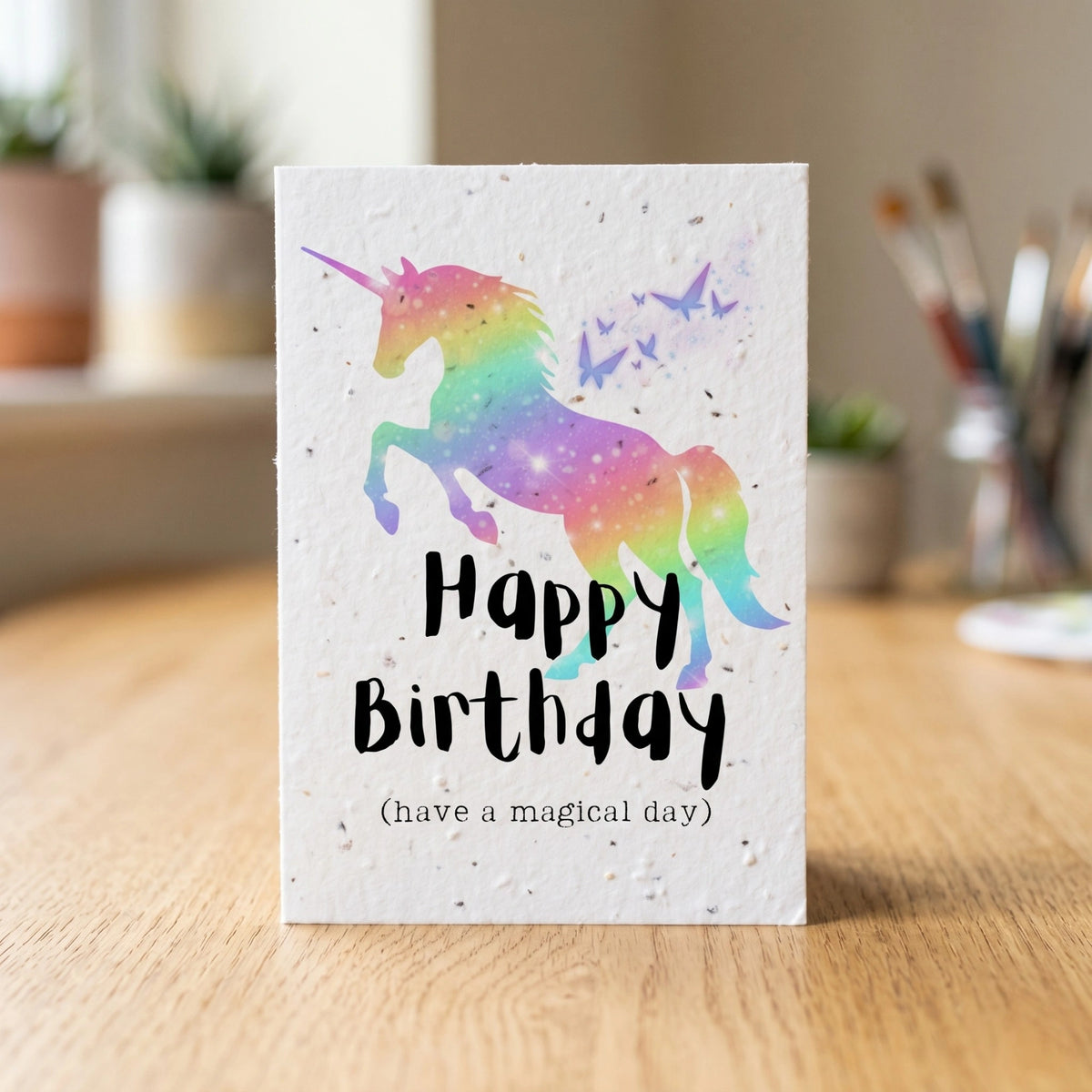 Greeting card with a colorful unicorn design and 'Happy Birthday' text on a wooden surface.