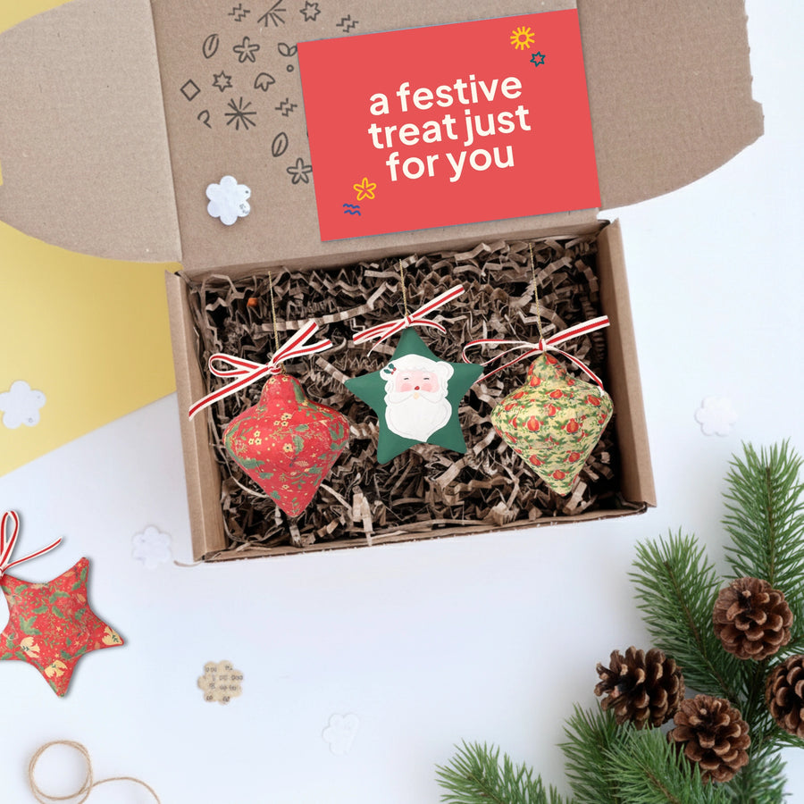 Box of decoupage Christmas ornaments with a festive card on a white background