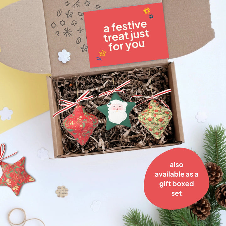 Box of upcycled Christmas decorations with a festive card on a white background