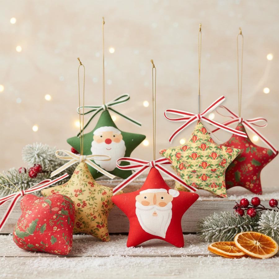 Star-shaped upcycled Christmas decorations with Santa faces and floral patterns on a wooden surface with lights in the background.