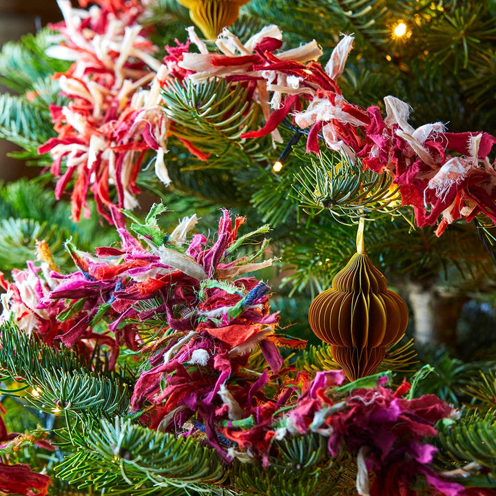 Decorative colourful fabric tinsel on a Christmas tree with colourful ornaments.