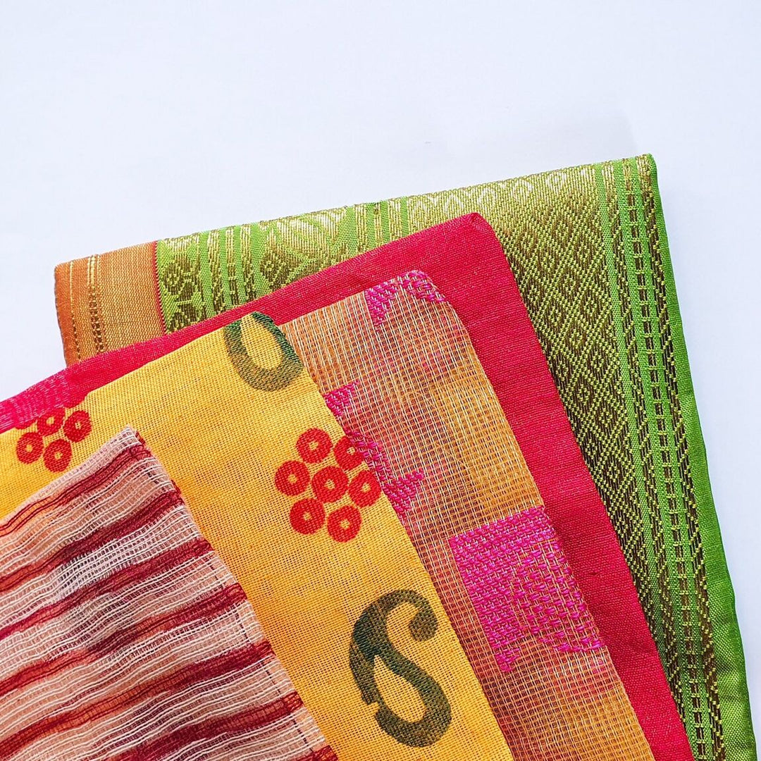 Stack of colourful sari fabric gift bags with various patterns on a light blue background