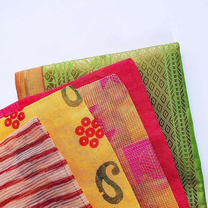 Stack of colourful sari fabric gift bags with various patterns on a light blue background