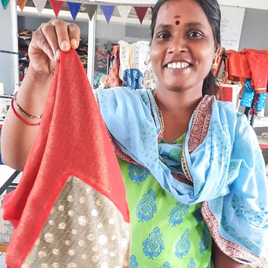Woman holding a red and gold fabric item in a workshop setting