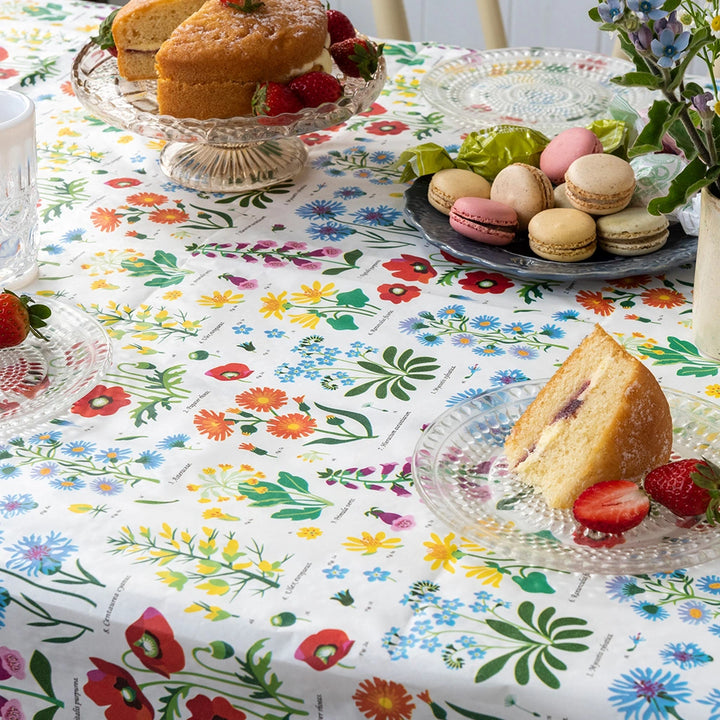 paper table cover with a colourful wild flowers design. The table is laid with celebration cakes and flowers 
