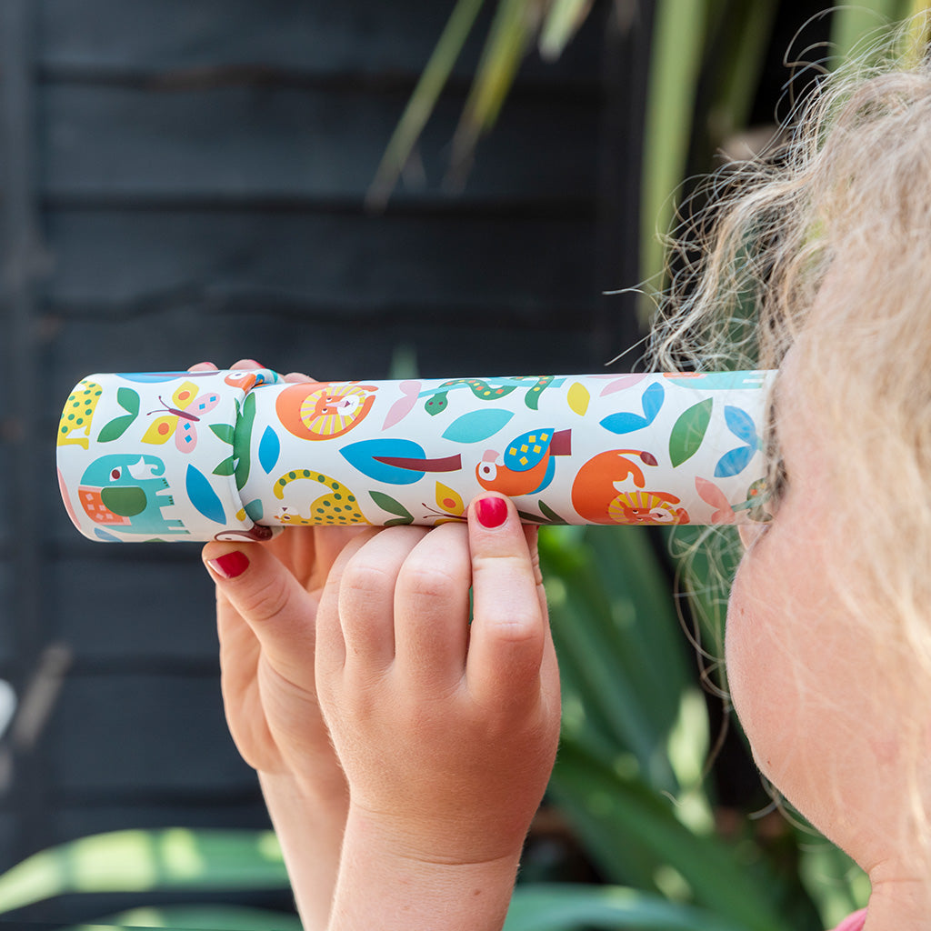 Child holding a colourful kaleidoscope with animal patterns against a blurred natural background