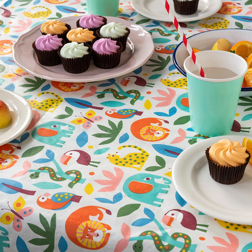 wild wonders paper table cover with colourful animal print in a retro style. The table cloth is on a table laid with party cakes and drinks. 