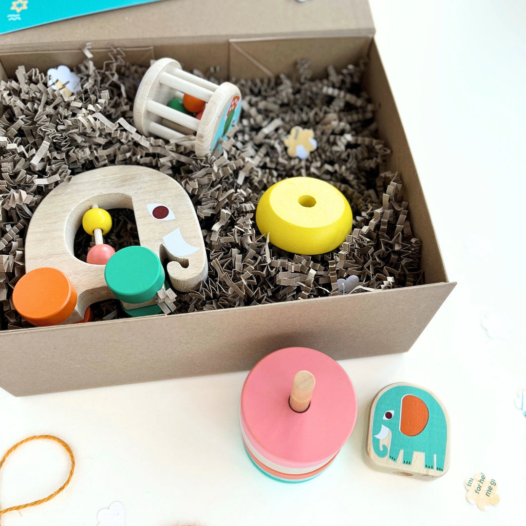Children's wooden toys including a colourful wooden stacker and pink and blue elephant toy in a craft gift box