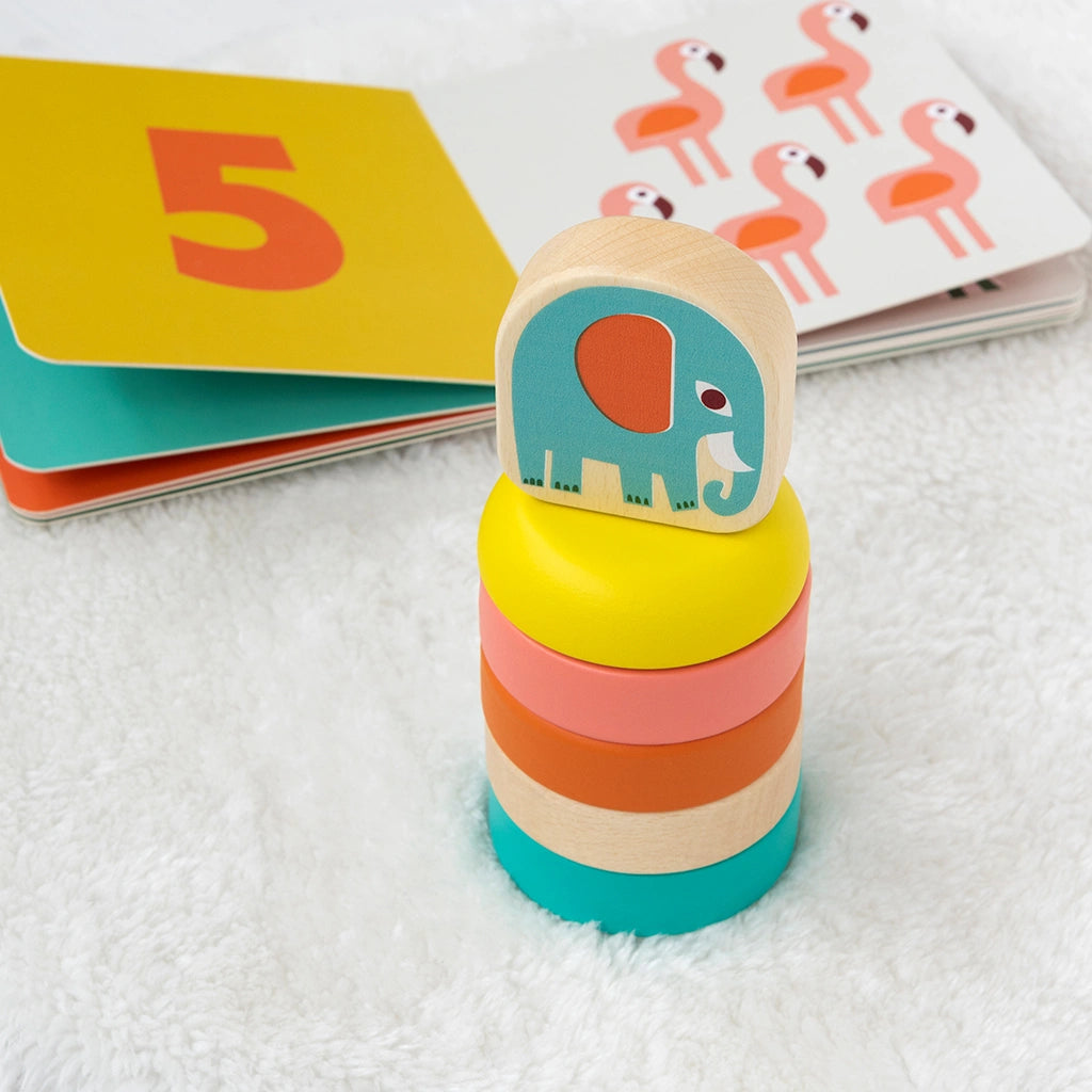 Stack of colorful wooden rings with an elephant design on top, next to children's books.