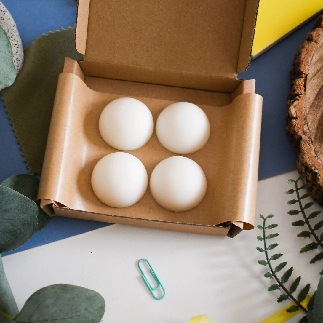 Four white wildflower wisp wax melts in a card gift box on a decorative surface with plants and ribbons.