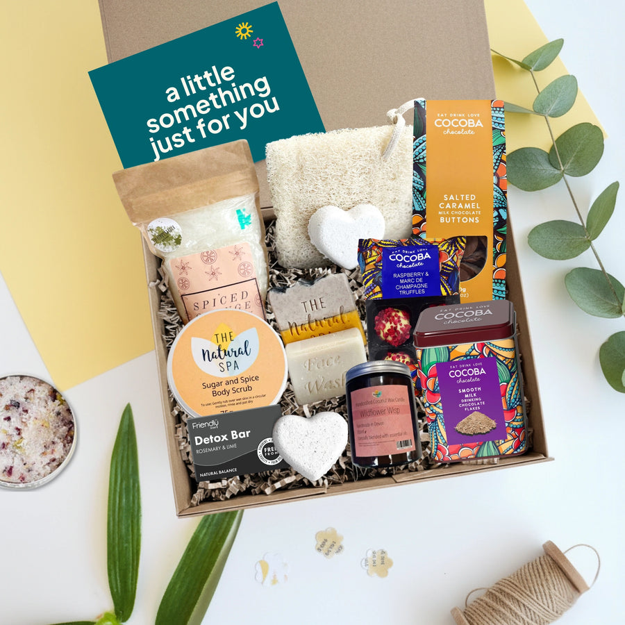 Winter self care pamper hamper with various items including bath bombs, body scrubs, and soaps on a light background.