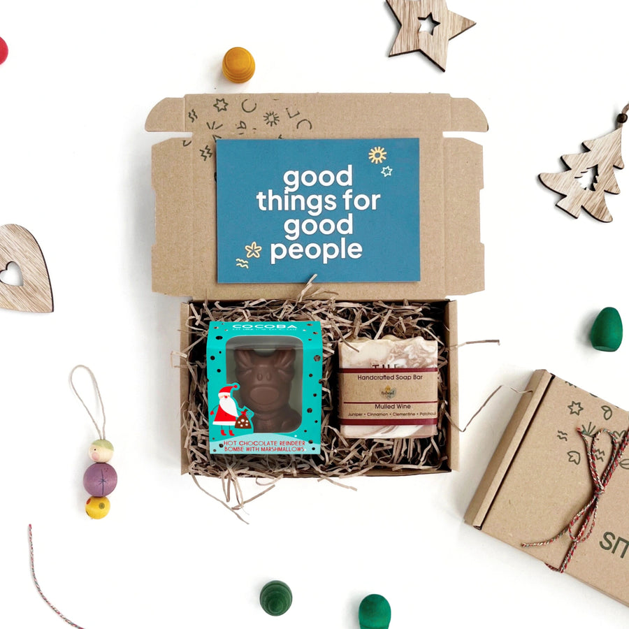 Gift box with 'good things for good people' card, reindeer hot chocolate bombe, and mulled wine soap on a white background