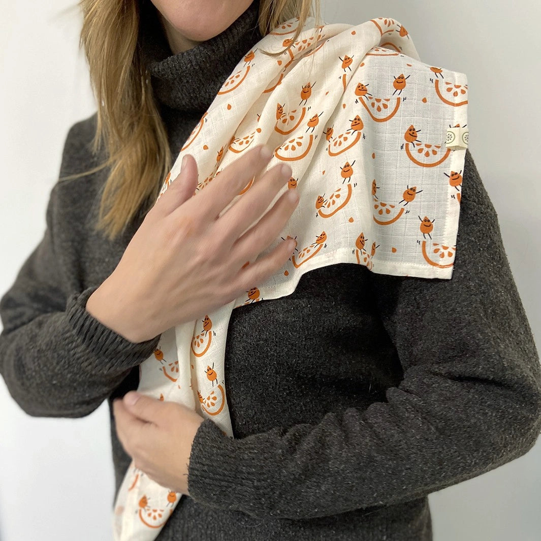 white woman wearing an orange printed muslin over her shoulder 