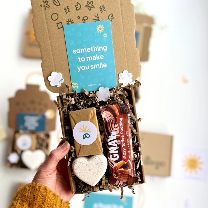 Deluxe Hug in a Box bespoke corporate gift Gift with chocolate bar, mini wrapped soap bar and heart shaped bath bomb inside, held by a womans hand.