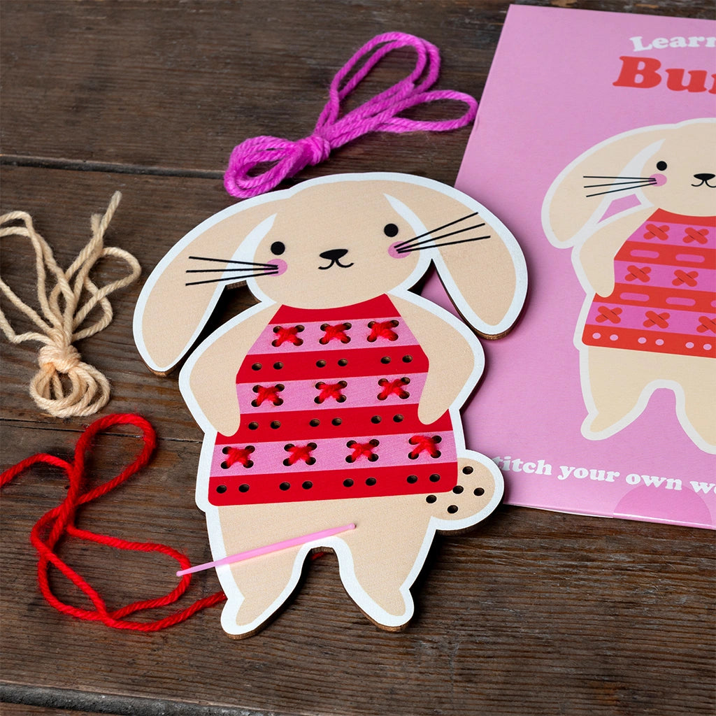 Bunny learn to sew Kit Contents on Wooden Table with the board in use. For developing fine motor skills and creativity.