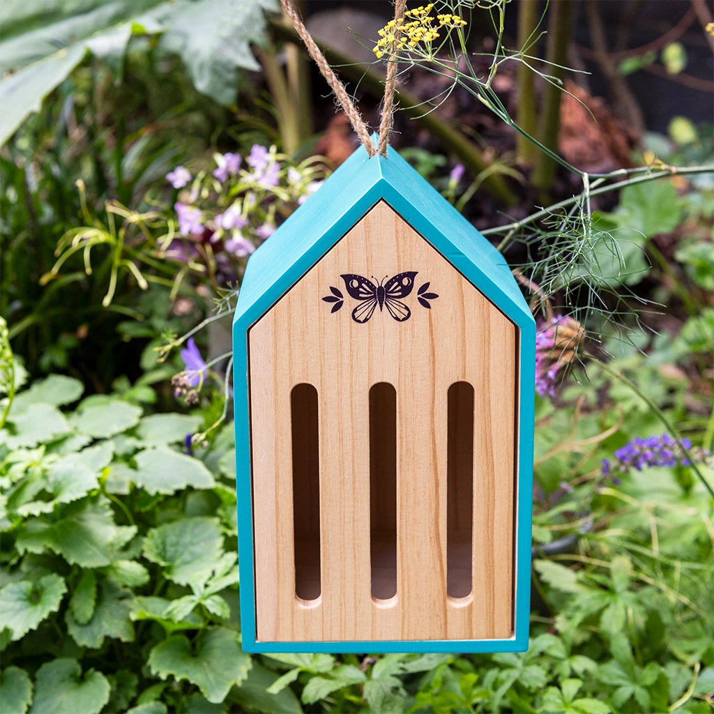 wooden butterfly hotel hanging outdoors in a shrub