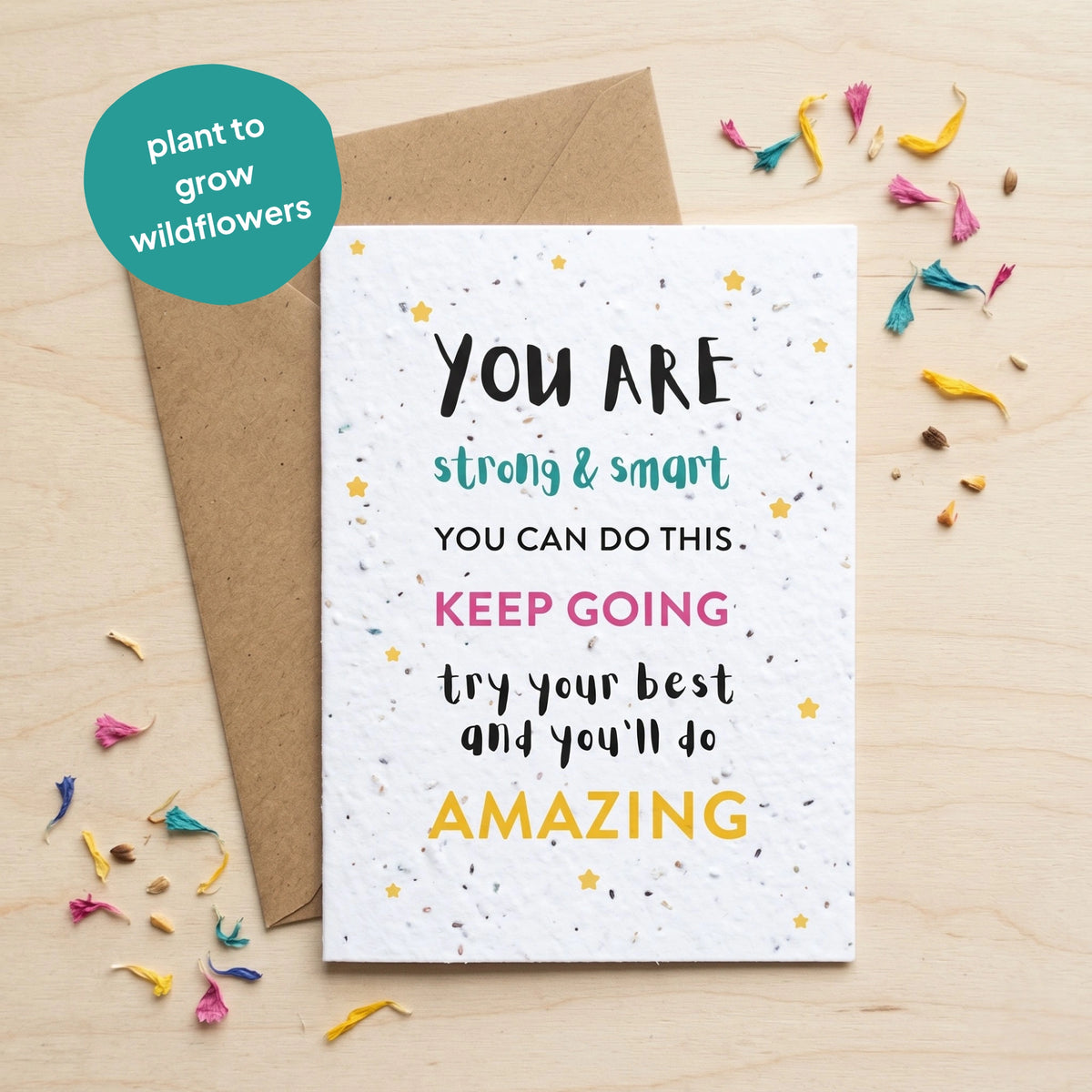 Motivational card with text on a wooden surface with wildflower seeds.