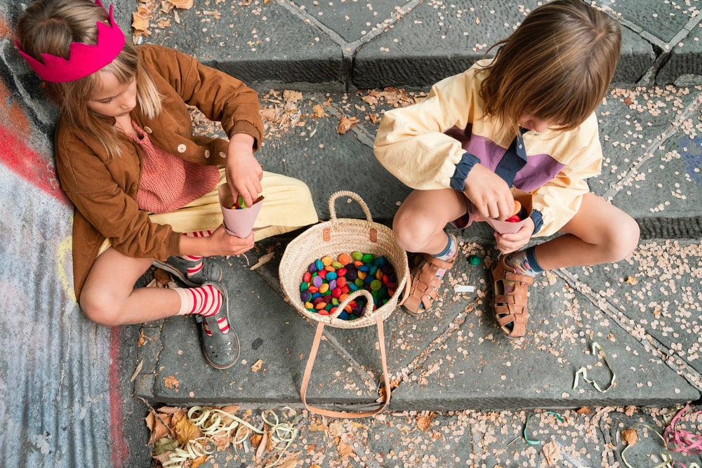 children sat on a pavement playing with Grapat wooden flowers in various rainbow colours