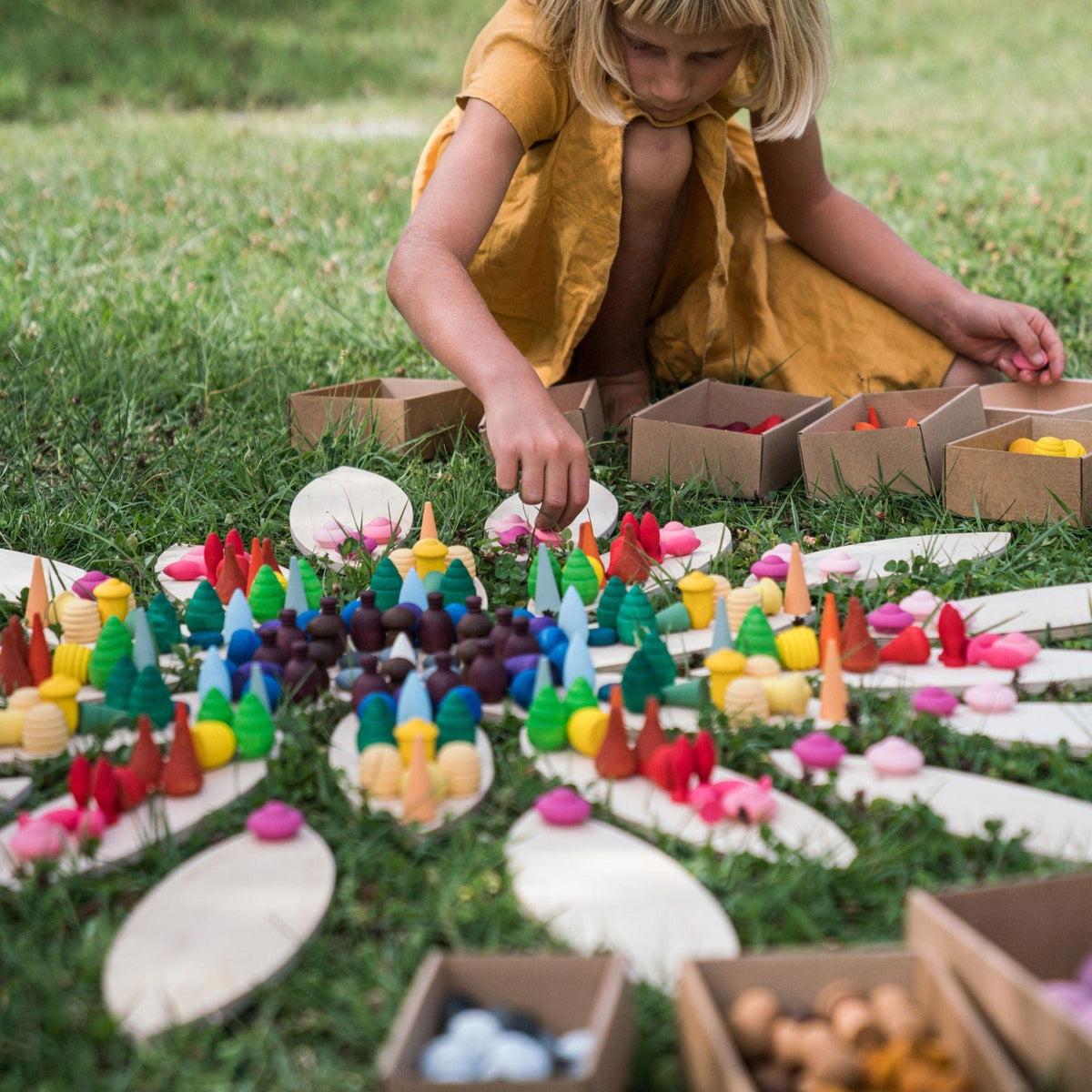 girl playing with colourful wodoen loose parts on a lawn 
