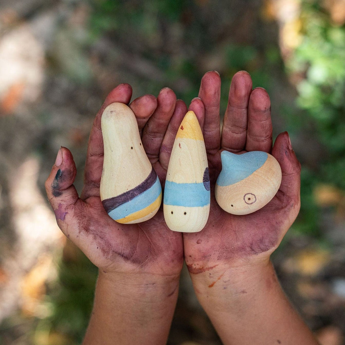 childs hands holding three wooden play figures from the Grapat Wow playset