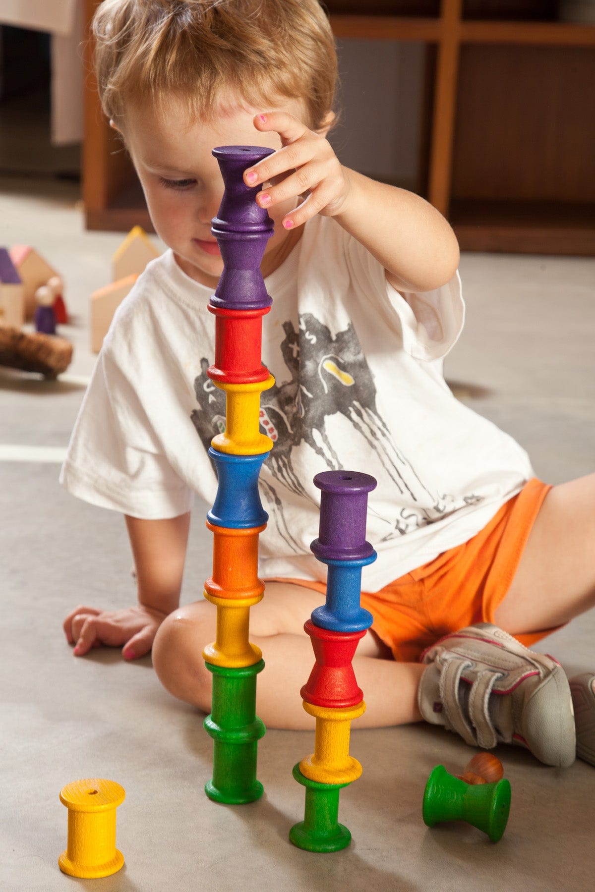child playing with grapat rainbow wooden spools