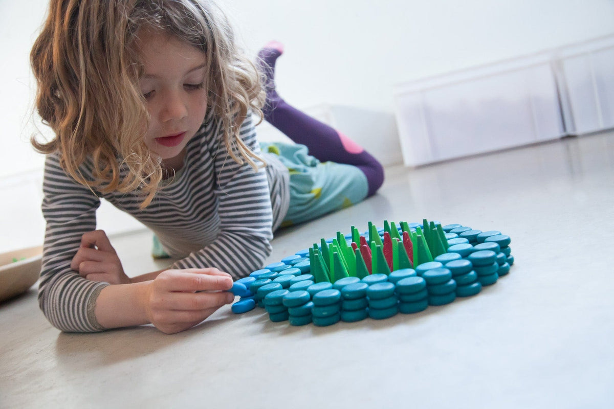 girl playing with Grapat Mandala Little Coins and other wooden loose parts