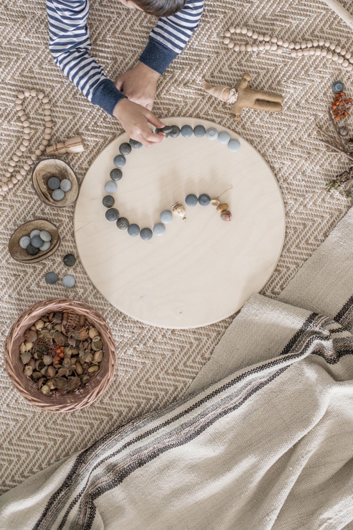 childs hands playing with grapat little stones loose parts on a neutral carpet 